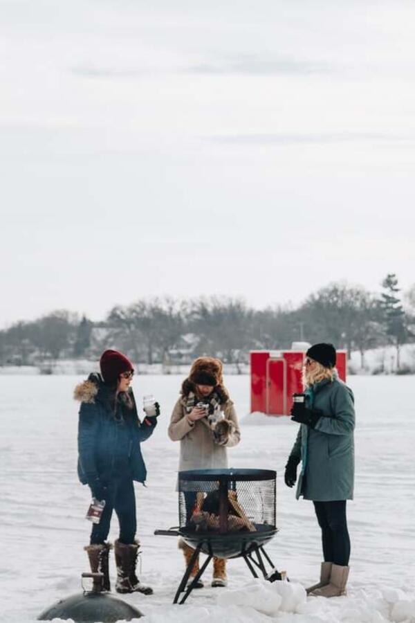 Friends having hot drinks on a frozen lake.